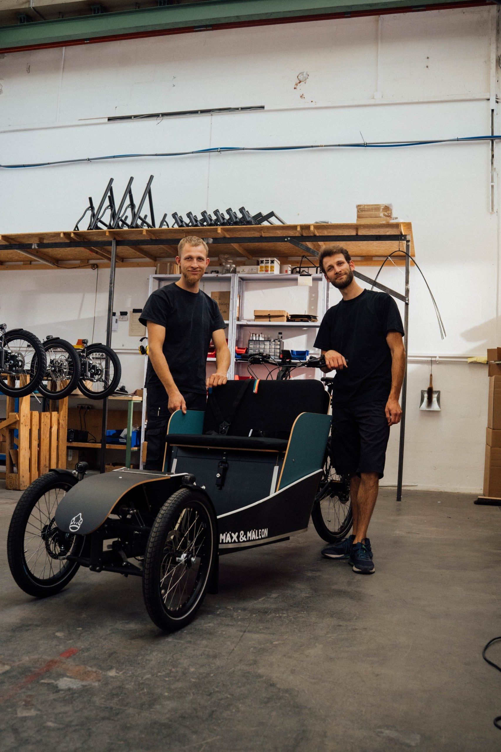 Zwei Mitarbeiter stehen stolz neben einem fertigen Passenger Bike