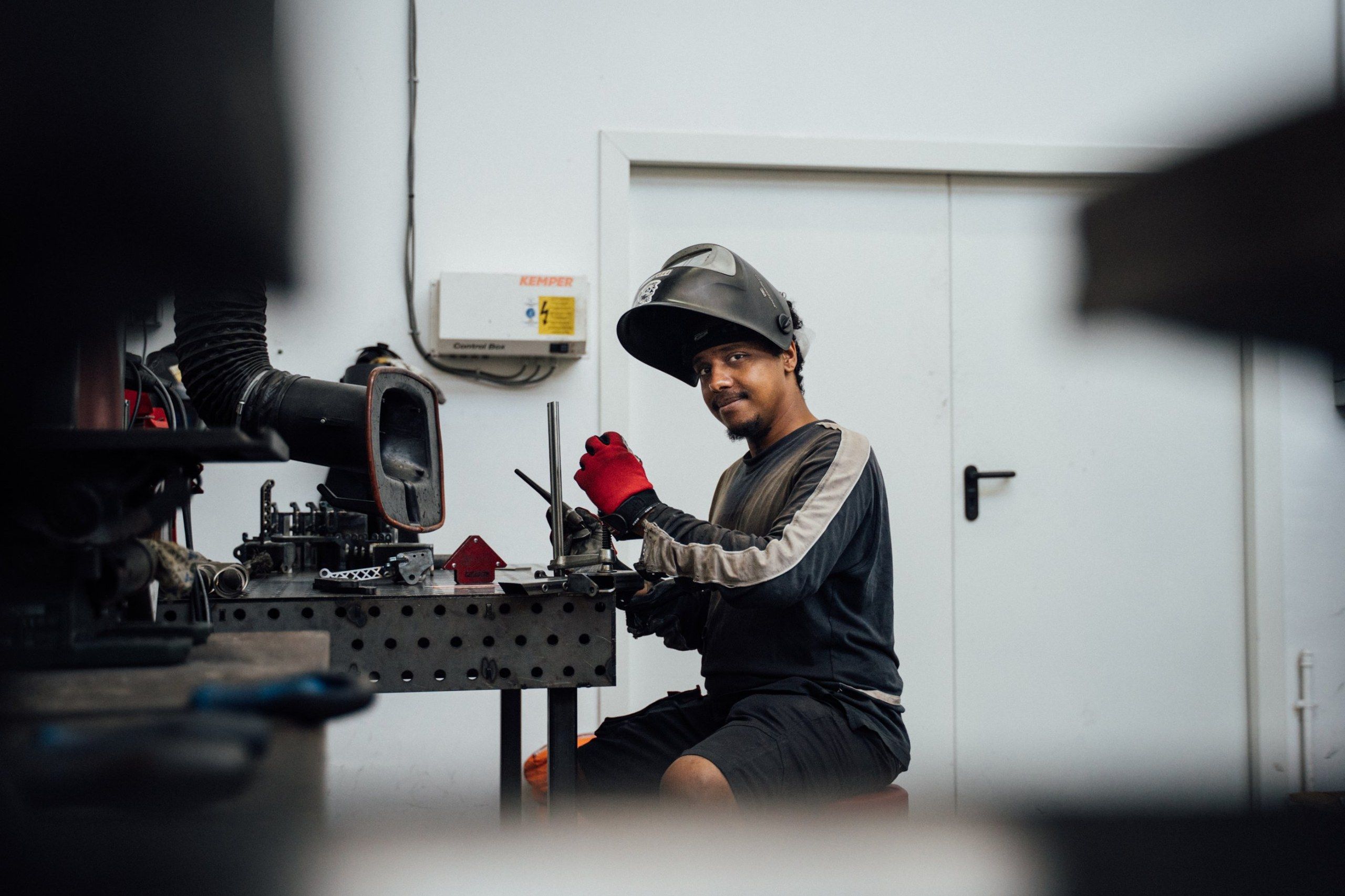 Schweißer mit hochgeklapptem Helm an seinem Arbeitstisch